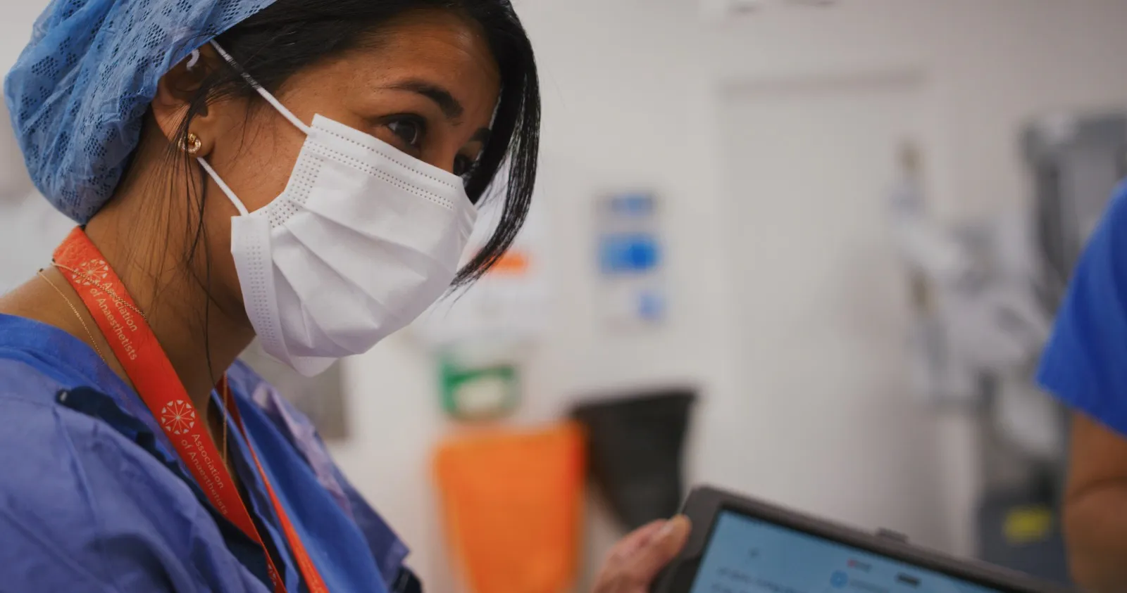 Ambulatory and outpatient care: a masked clinician reading CardMedic on a tablet.